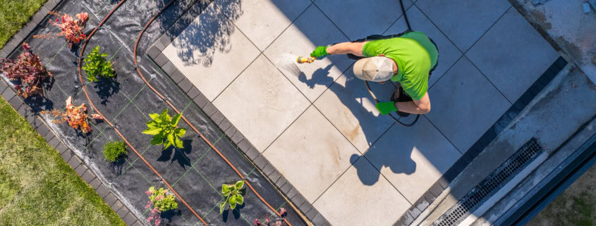 Homeowner cleans a patio from above. Backyard garden maintenance.