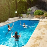 Woman throwing ball with son and daughter in swimming pool